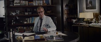 Movie still from “The Amazing Spider-Man” (2012), directed by Marc Webb – A man sitting at a table with a tablet; Medium shot, Low angle