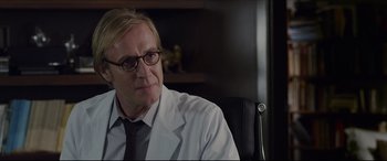 Movie still from “The Amazing Spider-Man” (2012), directed by Marc Webb – A man in a white lab coat sitting in a chair; Close Up shot, Over the shoulder angle