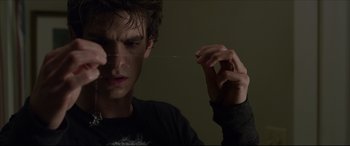Movie still from “The Amazing Spider-Man” (2012), directed by Marc Webb – A young man holding something in front of his face; Close Up shot, Over the shoulder angle