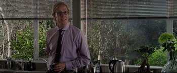 Movie still from “The Amazing Spider-Man” (2012), directed by Marc Webb – A man standing in front of a window holding a coffee cup; Medium shot, Over the shoulder angle