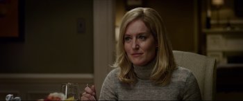 A woman sitting at a table with a glass of wine