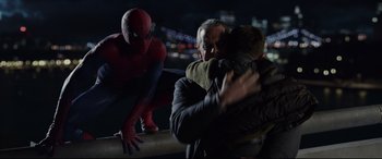 Movie still from “The Amazing Spider-Man” (2012), directed by Marc Webb – Two men hugging each other while a spider - man looks on; Medium shot, Over the shoulder angle