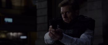 Movie still from “The Amazing Spider-Man” (2012), directed by Marc Webb – A man in a police vest holding a cell phone; Close Up shot, Over the shoulder angle