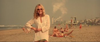 Movie still from “Blow” (2001), directed by Ted Demme – A woman in a white shirt is standing on the beach; Medium shot, Low angle