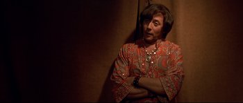 Movie still from “Blow” (2001), directed by Ted Demme – A man in an orange and red shirt with his arms crossed; Medium shot, Over the shoulder angle