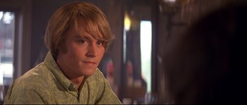 Movie still from “Blow” (2001), directed by Ted Demme – A man with blonde hair and a green shirt; Close Up shot, Over the shoulder angle