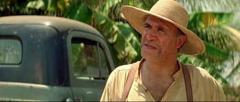 Movie still from “Blow” (2001), directed by Ted Demme – An older man wearing a straw hat standing in front of a car; Close Up shot, Low angle