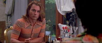 Movie still from “Blow” (2001), directed by Ted Demme – A man sitting at a table in front of a wine glass; Close Up shot, Over the shoulder angle