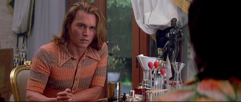 Movie still from “Blow” (2001), directed by Ted Demme – A man sitting at a table in front of a mirror; Medium shot, Over the shoulder angle