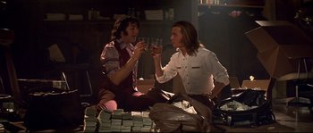Movie still from “Blow” (2001), directed by Ted Demme – Two men sitting next to each other holding wine glasses; Medium shot, Low angle