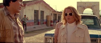 Movie still from “Blow” (2001), directed by Ted Demme – A woman standing in front of an old car; Medium shot, Low angle
