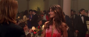 Movie still from “Blow” (2001), directed by Ted Demme – A woman in a red dress standing in front of a group of people; Medium shot, Over the shoulder angle