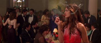 Movie still from “Blow” (2001), directed by Ted Demme – A woman smoking a cigarette in front of other people; Medium shot, Over the shoulder angle