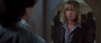 Movie still from “Blow” (2001), directed by Ted Demme – A man with long blonde hair standing next to another man; Close Up shot, Over the shoulder angle