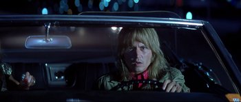 Movie still from “Blow” (2001), directed by Ted Demme – A man with long blonde hair sitting in the back of a car at night; Close Up shot, Low angle