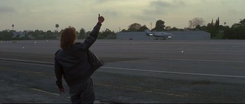 Movie still from “Blow” (2001), directed by Ted Demme – A person standing on the side of a road with their hand up; Wide shot, Low angle