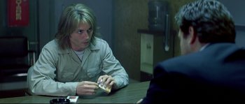 Movie still from “Blow” (2001), directed by Ted Demme – A man sitting at a table with a cigarette in his hand; Medium shot, Over the shoulder angle