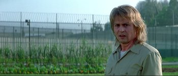 Movie still from “Blow” (2001), directed by Ted Demme – A man standing next to a fence in front of a field; Close Up shot, Low angle