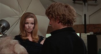 Movie still from “Blow-Up” (1966), directed by Michelangelo Antonioni – A man and a woman standing next to each other under an umbrella; Medium shot, Over the shoulder angle