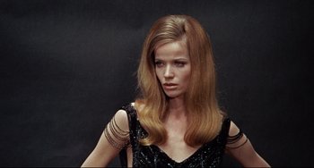 Movie still from “Blow-Up” (1966), directed by Michelangelo Antonioni – A woman in a black dress is posing for a picture; Close Up shot, High angle