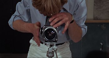 Movie still from “Blow-Up” (1966), directed by Michelangelo Antonioni – A man holding a camera up to his face; Extreme Close Up shot, Overhead angle