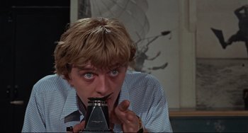 Movie still from “Blow-Up” (1966), directed by Michelangelo Antonioni – A man holding an object up to his mouth; Close Up shot, Low angle