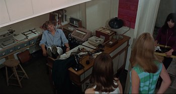 Movie still from “Blow-Up” (1966), directed by Michelangelo Antonioni – A man sitting at a desk in front of a woman; Wide shot, High angle