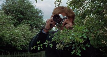 Movie still from “Blow-Up” (1966), directed by Michelangelo Antonioni – A man taking a picture with a camera in a tree; Close Up shot, Low angle