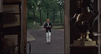 Movie still from “Blow-Up” (1966), directed by Michelangelo Antonioni – A man walking down the street holding a cell phone; Wide shot, Low angle