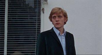 Movie still from “Blow-Up” (1966), directed by Michelangelo Antonioni – A man in a suit and tie standing in front of a window; Close Up shot, Low angle