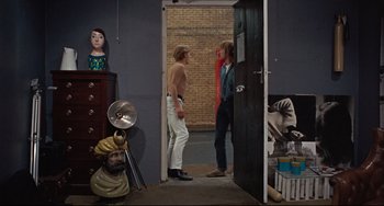 Movie still from “Blow-Up” (1966), directed by Michelangelo Antonioni – Two people standing in a room talking to each other; Wide shot, Over the shoulder angle