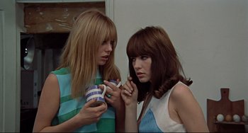 Two young women holding coffee cups and looking at each other