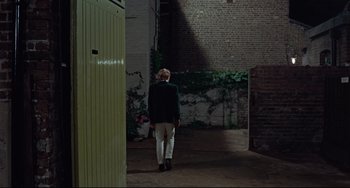 Movie still from “Blow-Up” (1966), directed by Michelangelo Antonioni – A person standing in a room with a brick wall; Wide shot, High angle