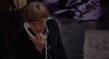 Movie still from “Blow-Up” (1966), directed by Michelangelo Antonioni – A man in a suit talking on a phone; Close Up shot, High angle