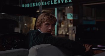 Movie still from “Blow-Up” (1966), directed by Michelangelo Antonioni – A man sitting in the back seat of a car at night; Medium shot, Over the shoulder angle