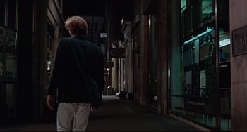 Movie still from “Blow-Up” (1966), directed by Michelangelo Antonioni – A person walking down a street at night; Wide shot, Over the shoulder angle