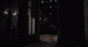 Movie still from “Blow-Up” (1966), directed by Michelangelo Antonioni – A person is walking in a dark alley way; Wide shot, High angle