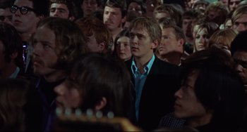 Movie still from “Blow-Up” (1966), directed by Michelangelo Antonioni – A man in a crowd of people wearing a black suit; Medium shot, High angle