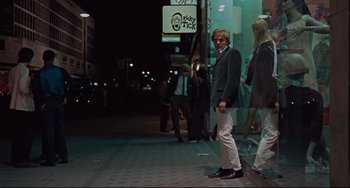 Movie still from “Blow-Up” (1966), directed by Michelangelo Antonioni – A man standing on the side of the street at night; Wide shot, Low angle
