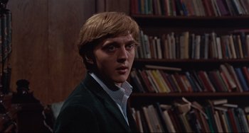 Movie still from “Blow-Up” (1966), directed by Michelangelo Antonioni – A man in a green jacket in front of bookshelves; Close Up shot, Low angle