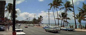 Movie still from “Blue Hawaii” (1961), directed by Norman Taurog – Cars are driving down the road near the ocean; Extreme Wide shot, High angle