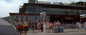 Movie still from “Blue Hawaii” (1961), directed by Norman Taurog – A group of people standing in front of a building; Extreme Wide shot, Low angle