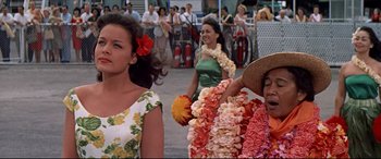 Movie still from “Blue Hawaii” (1961), directed by Norman Taurog – A group of women walking down a street with flowers in their hair; Medium shot, Over the shoulder angle