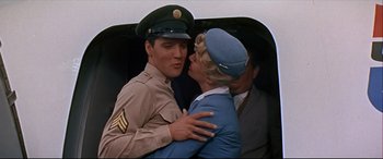 Movie still from “Blue Hawaii” (1961), directed by Norman Taurog – A man and a woman kissing in front of another man and a woman; Medium shot, Low angle