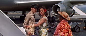 Movie still from “Blue Hawaii” (1961), directed by Norman Taurog – A man and a woman are standing in front of an airplane; Medium shot, Over the shoulder angle
