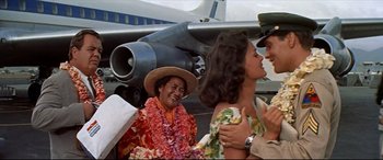 Movie still from “Blue Hawaii” (1961), directed by Norman Taurog – A group of people standing next to an airplane; Medium shot, Over the shoulder angle