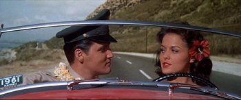 Movie still from “Blue Hawaii” (1961), directed by Norman Taurog – A man and a woman sitting in the back seat of a car; Medium shot, Low angle