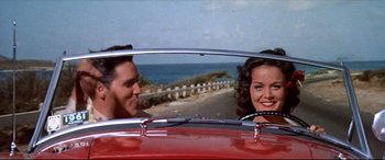 Movie still from “Blue Hawaii” (1961), directed by Norman Taurog – A man and a woman in a red car looking out the window; Medium shot, Low angle