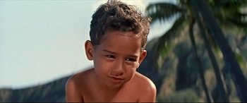 Movie still from “Blue Hawaii” (1961), directed by Norman Taurog – A young child with a palm tree in the background; Close Up shot, Low angle