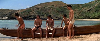 Movie still from “Blue Hawaii” (1961), directed by Norman Taurog – A group of young men sitting on top of a canoe; Wide shot, Low angle